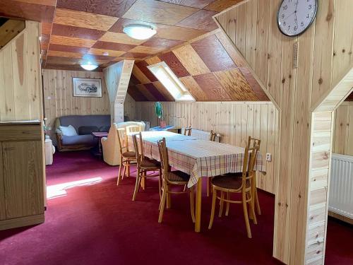 a dining room with a table and chairs and a clock at Chata Severka s Wellness in Rokytnice v Orlických Horách