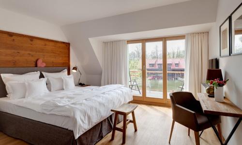 a bedroom with a bed and a desk and a window at Hotel Strandhaus - Boutique Resort & Spa in Lübben