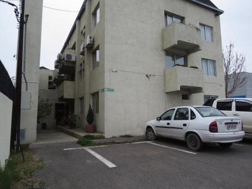 a white car parked in a parking lot in front of a building at Hotel Doria in Rancagua