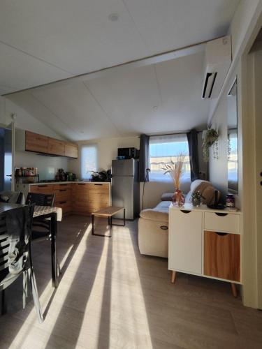 Il dispose d'une cuisine et d'un salon avec une table et un réfrigérateur. dans l'établissement Mobilehome cosy, à Biscarrosse