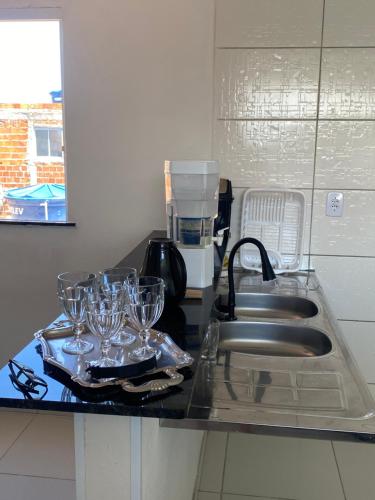 a kitchen counter with glasses on a tray next to a sink at Apto em Itaparica condomínio in Itaparica Town
