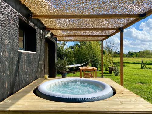un bain à remous sur une terrasse en bois avec une pergola dans l'établissement Tiny house avec spa en Dordogne, à Saint-Seurin-de-Prats