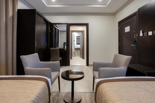 a hotel room with two beds and chairs and a table at Hotel SDU BOUTIQUE in Al Madinah