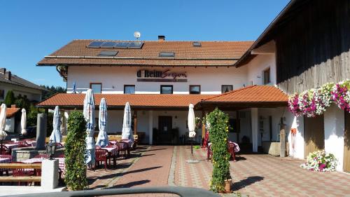 a hotel with tables and chairs and umbrellas in front of it at Gasthof Pension Gregori in Bad Koetzting
