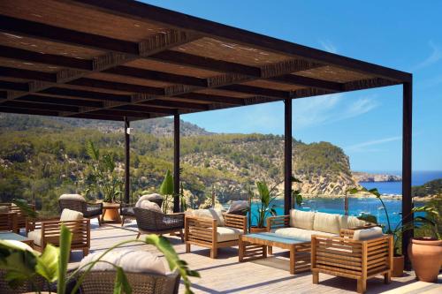a patio with furniture and a view of the ocean at Cala San Miguel Ibiza Resort, Adults only, Curio Collection by Hilton in Puerto de San Miguel