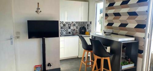 - une petite cuisine avec un comptoir et des tabourets dans la chambre dans l'établissement Design appartement - 4pers - Histoire de Clés, au Cap d'Agde