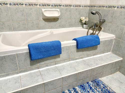 a bathroom with a bath tub with blue towels on it at Mellieha Seaside Apartment in Mellieħa