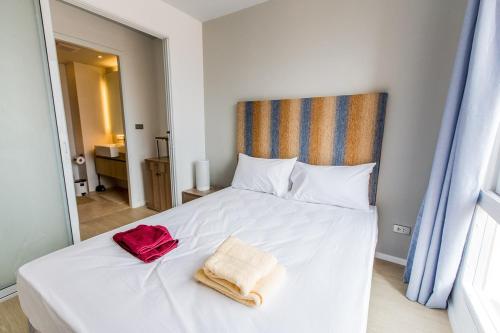 a bedroom with a white bed with a red bag on it at Atlantis Condo Resort by Anatolii in Jomtien Beach
