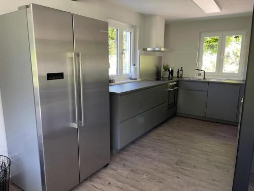 una cucina con un grande frigorifero in acciaio inossidabile di Freistehendes Ferienhaus mit Kamin, Sauna, atemberaubenden Blick ins Tal, mehrere Terrassen, 1500qm Grundstück 1,6m hoch eingezäunt a Gerabronn