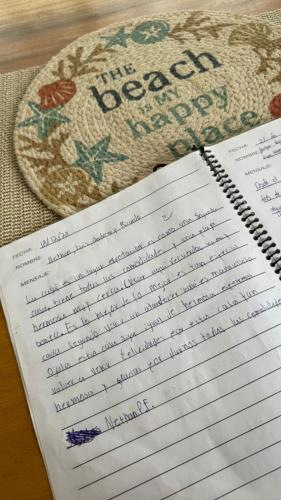 a notebook with writing on it next to a hat at La Casa de Papi. in Parrita