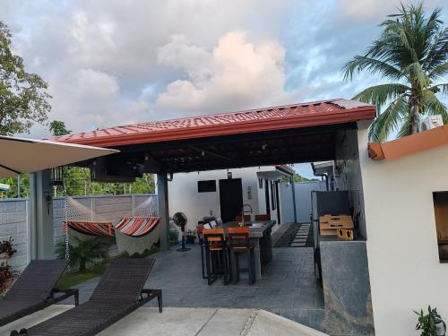 a patio with a table and chairs under a roof at La Casa de Papi. in Parrita