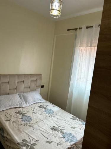 a bedroom with a bed with a floral bedspread and a window at Le nid zen in Marrakech
