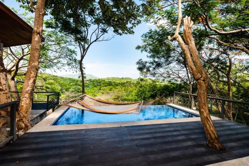 a hammock in the trees next to a swimming pool at Hammock House Your Private Oasis Near Tamarindo in Villarreal