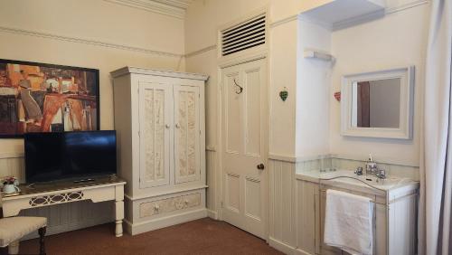bagno con lavandino e TV a parete di OYO Cornerstone Manor Hotel a Sale