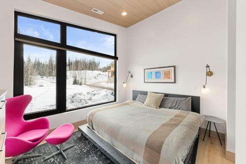 ein Schlafzimmer mit einem großen Fenster und einem Bett und einem rosa Stuhl in der Unterkunft Modern Ski-InandOut Home in Brian Head with Deck in Brian Head