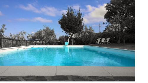 a blue swimming pool with two chairs and a tree at Podere Campriano Winery Adult only in Greve in Chianti