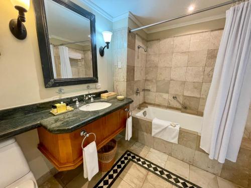a bathroom with a sink and a tub and a mirror at Pierre Mundo Imperial Riviera Diamante Acapulco All Inclusive in Acapulco
