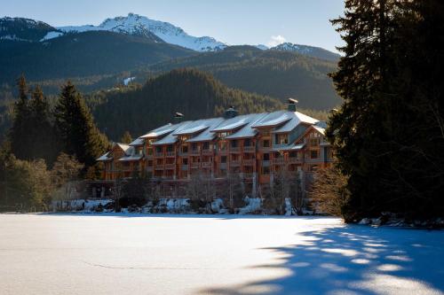 a large building in the mountains with snow on the ground at Nita Lake Lodge in Whistler