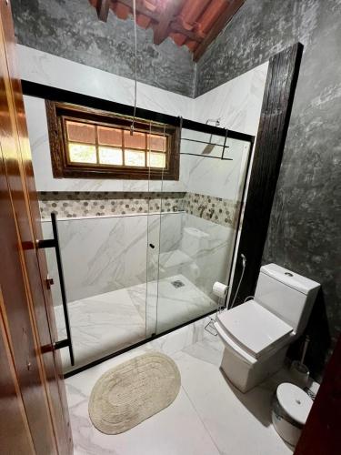 a bathroom with a glass shower and a toilet at Casa Mirante do Capão in Palmeiras