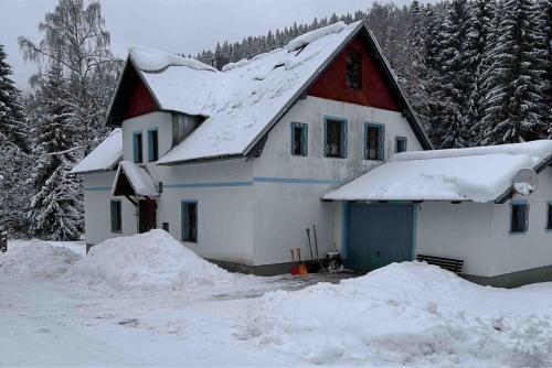 a white house with a red roof in the snow at Chata Zlatý Kopec in Boží Dar