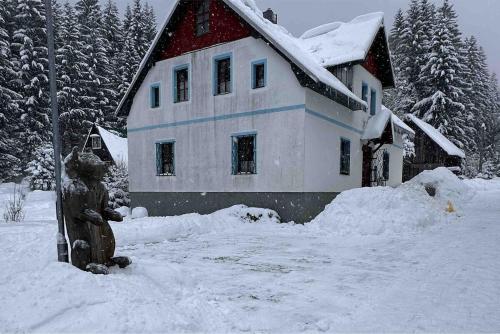 a house covered in snow with a statue in front of it at Chata Zlatý Kopec in Boží Dar