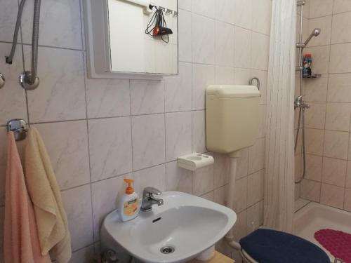 a bathroom with a sink and a toilet and a mirror at Apartman Olly in Klek