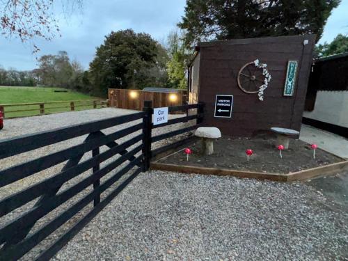 a fence with red flowers in front of a building at The Hideaway Glamping Pod 2 With Hot Tub & Cold Shower in Naas