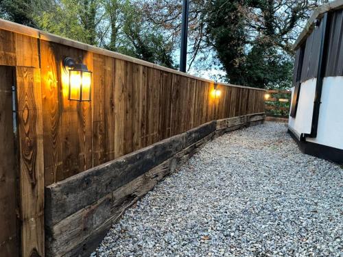 a wooden fence with lights on the side of it at The Hideaway Glamping Pod 2 With Hot Tub & Cold Shower in Naas