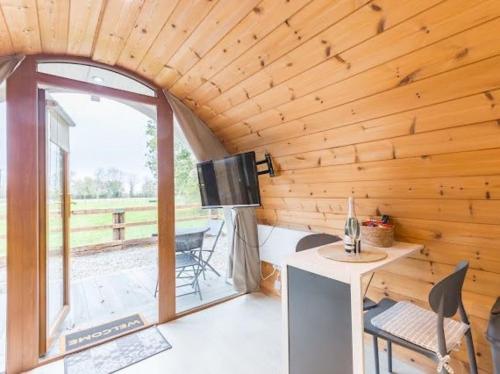 a wooden cabin with a table and a window at The Hideaway Glamping Pod 2 With Hot Tub & Cold Shower in Naas