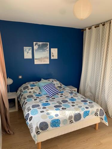 une chambre avec un lit avec un mur bleu dans l'établissement Villa bord de mer au Grau d 'Agde 140 m2, au Grau-dʼAgde