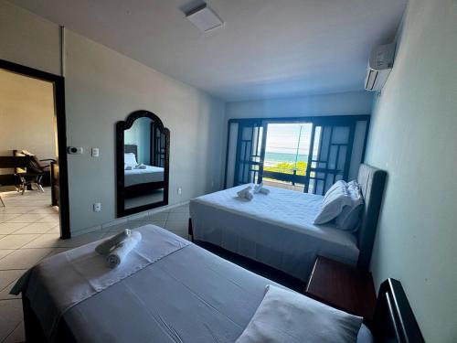ein Hotelzimmer mit zwei Betten und einem Spiegel in der Unterkunft Casa Frente Mar na Avenida Beira Mar 3 Itapoa in Itapoa