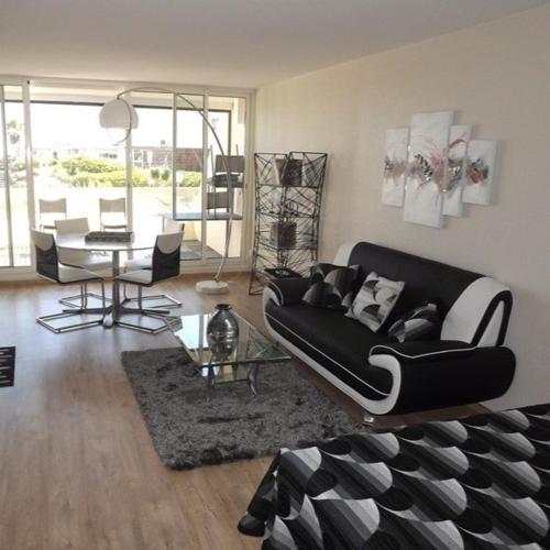 un salon avec un canapé noir et une table dans l'établissement Studio Graphik - Héliopolis C 74 - Luxe - 2 personnes, au Cap d'Agde