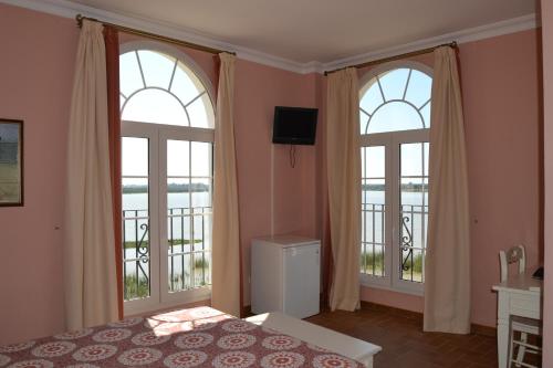 a bedroom with two windows and a bed and a television at Hotel Restaurante Toruño in El Rocío