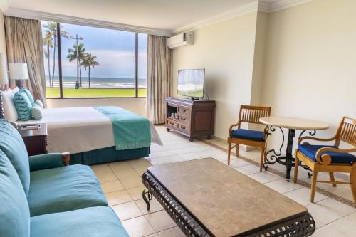 a hotel room with a bed and a tv and a couch at Pierre Mundo Imperial Riviera Diamante Acapulco All Inclusive in Acapulco