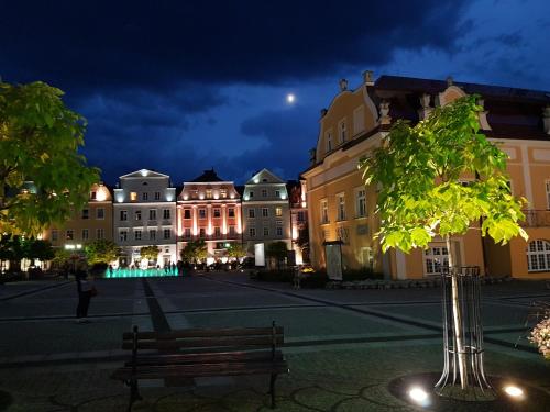 a city street at night with a bench and buildings at Apartament Przy Starówce - Bella in Bolesławiec