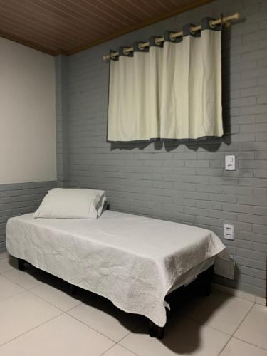 a bed in a room with a window with a white bedspread at POUSADA SOL e LUAR in Santo Amaro