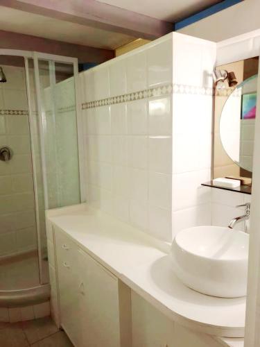 une salle de bain blanche avec un lavabo et une douche dans l'établissement Au petit bonheur parking gratuit, à Cavalaire-sur-Mer