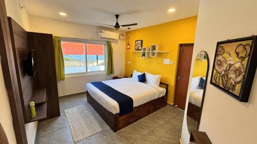 a bedroom with a bed with yellow walls and a window at Ta Cabana Beach house-Pondicherry in Pondicherry