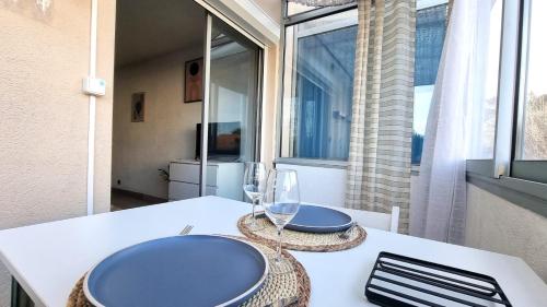 - une table avec deux assiettes bleues et des verres à vin dans l'établissement Appartement Mer T2 Grau d 'Agde, au Grau-dʼAgde