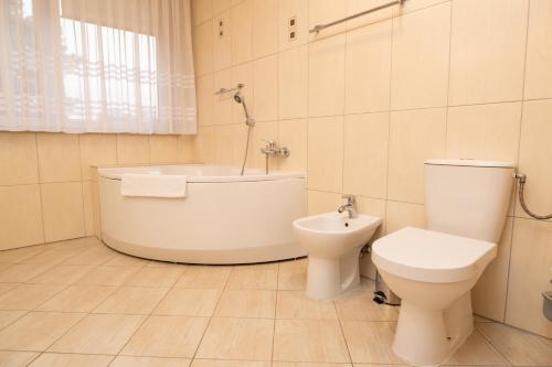 a bathroom with a toilet and a tub and a sink at Hotel Wilga by Katowice Airport in Pyrzowice