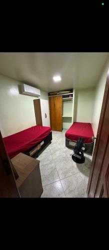 a room with two beds with red sheets at Apartamento 2 quartos Piúma in Piúma
