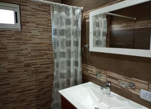 een badkamer met wastafel en douche met spiegel bij cabañas sunrise in Merlo