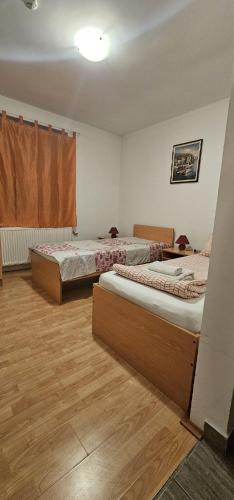two beds in a room with wooden floors at Vila Vienna in Zaječar