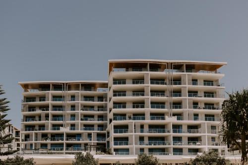 a tall white apartment building with balconies at Sand Dunes at Bok Beach in Kawana Waters