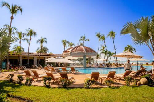 a pool at a resort with chairs and umbrellas at Pierre Mundo Imperial Riviera Diamante Acapulco All Inclusive in Acapulco