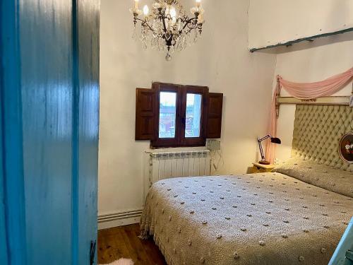 a bedroom with a bed and a window and a chandelier at Riojania Heredad in Santa Eulalia Bajera