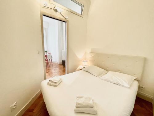 une chambre avec un lit blanc et un miroir dans l'établissement Belle Nuit, à Nice