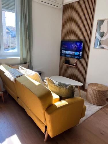 a living room with a yellow couch and a table at Le Jardin Secret F3 Elégance comfort in Delle