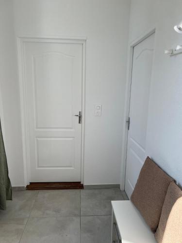 a room with a white door and a couch at Le Jardin Secret F3 Elégance comfort in Delle