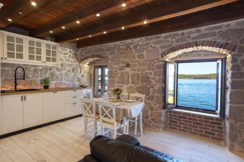 Apartman Sun 1 في شيبينيك: مطبخ مع طاولة وجدار حجري